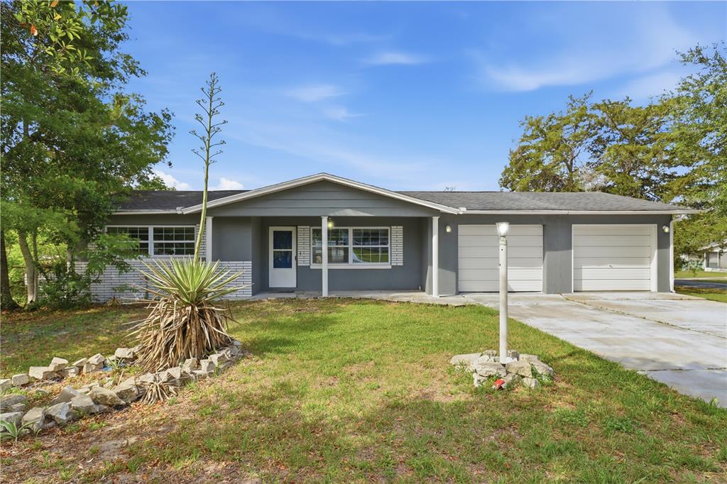 A single-story gray house with a two-car garage and a front yard with landscaping — 38 REGINA BOULEVARD, BEVERLY HILLS, FL