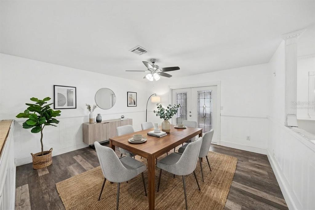 A dining room with a wooden table, gray chairs, a jute rug, and white wainscoting — 10938 SALT TREE DRIVE, PORT RICHEY, FL
