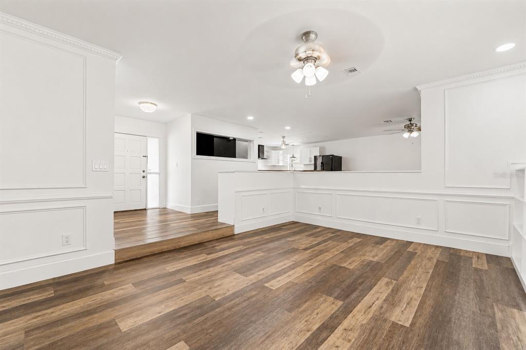 A living room with wood-look flooring, white wainscoting, and a raised entryway — 10938 SALT TREE DRIVE, PORT RICHEY, FL