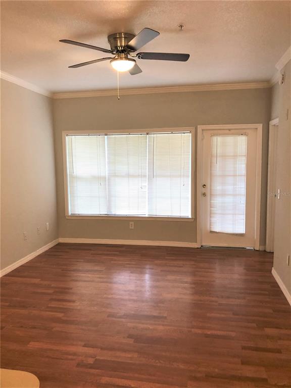 An empty room features wood-look flooring, a ceiling fan, large windows, and a glass-paneled door — 3725 CONROY ROAD UNIT 2113, ORLANDO, FL