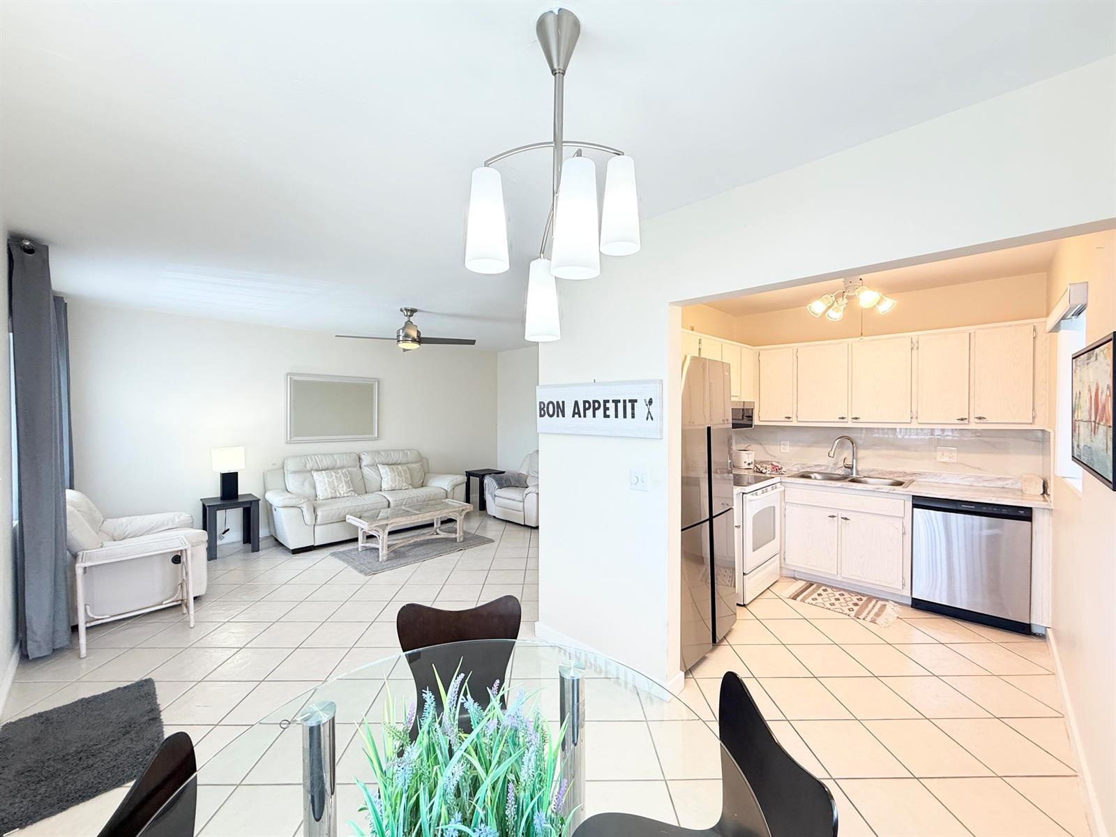 An open-concept living room and kitchen featuring white cabinetry, tile flooring, and a dining area — 2880 Lake Osborne Drive # 205, FL 33461, FL