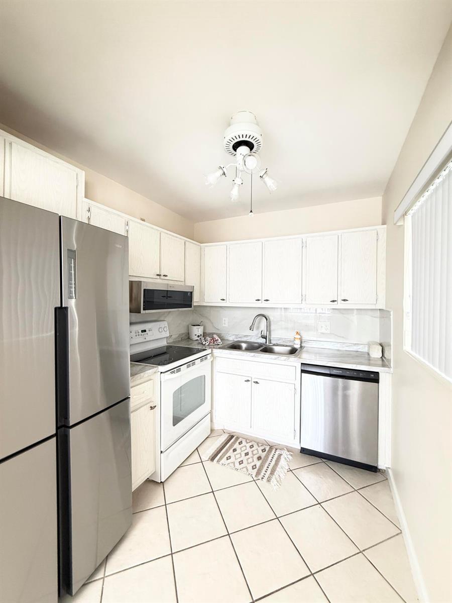 A kitchen features white cabinets, stainless steel appliances, a tile floor, and a ceiling light — 2880 Lake Osborne Drive # 205, FL 33461, FL