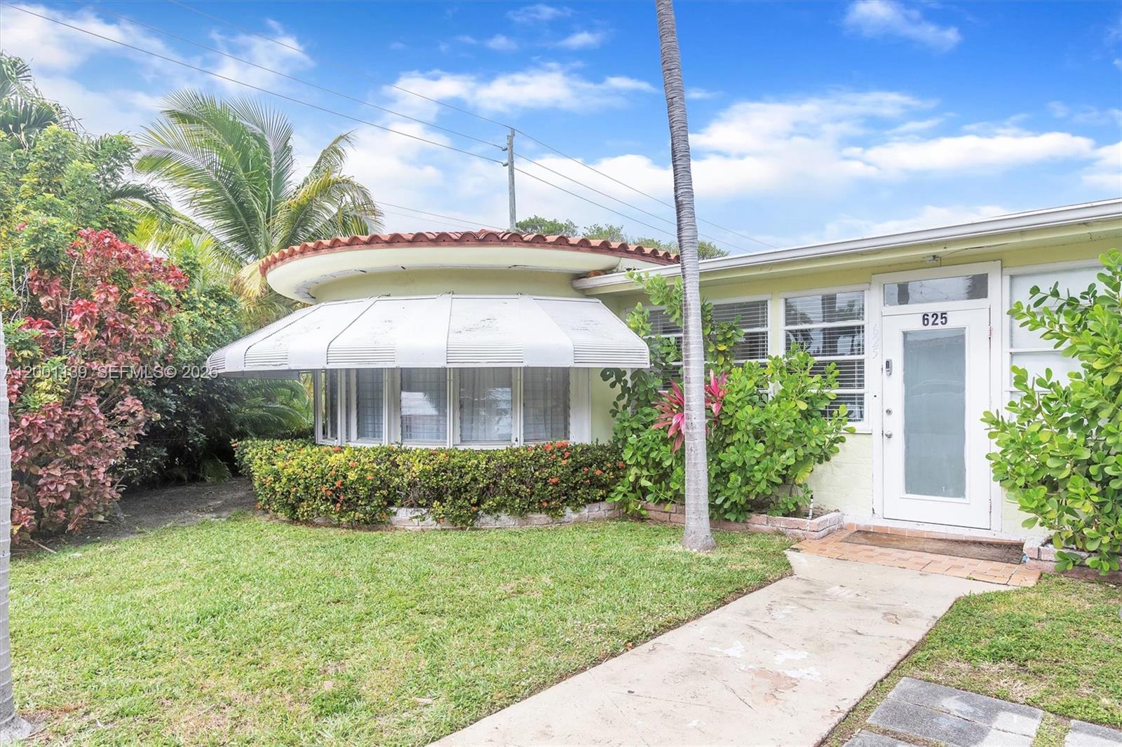 A single-story house features a curved bay window with a metal awning and tile roof — 625 93rd St, Surfside FL 33154, SURFSIDE, FL
