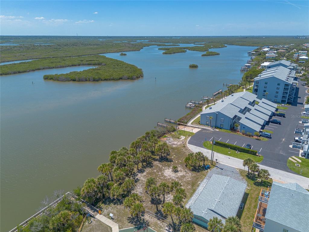 An aerial view shows a waterfront condominium complex with a parking lot and mangroves — 0 LADYFISH AVENUE, NEW SMYRNA BEACH, FL