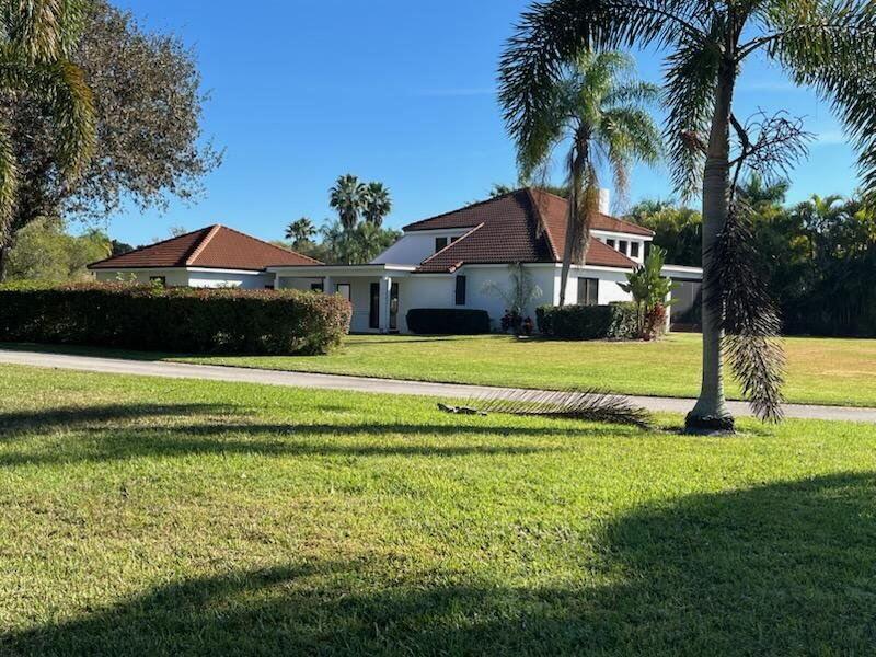 A white house with a brown tiled roof sits on a large, grassy lawn — 2990 Conifer Drive, Fort Pierce FL 34951, FORT PIERCE, FL