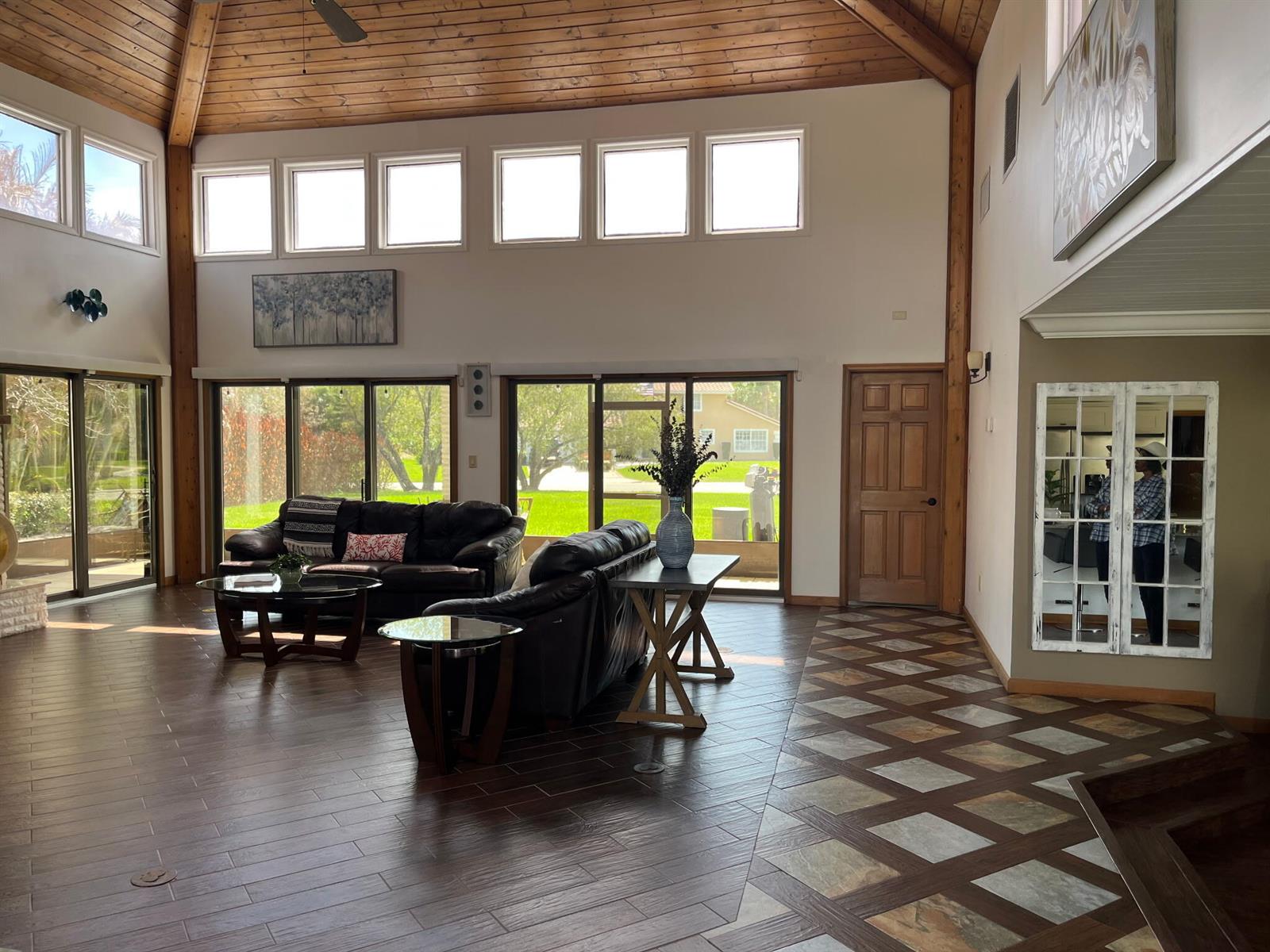 A spacious living room features vaulted wood ceilings, dark leather furniture, and mixed tile flooring — 2990 Conifer Drive, Fort Pierce FL 34951, FORT PIERCE, FL