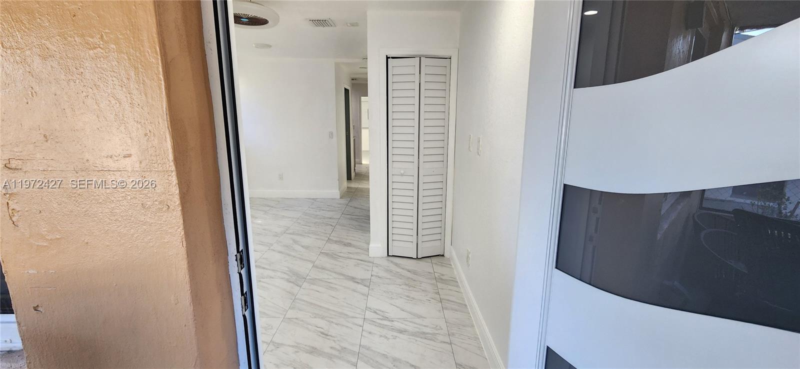 A white door opens into a hallway with white marble-patterned tile flooring and a closet — 1490/1492 NW 38th St, Miami FL 33142, MIAMI, FL