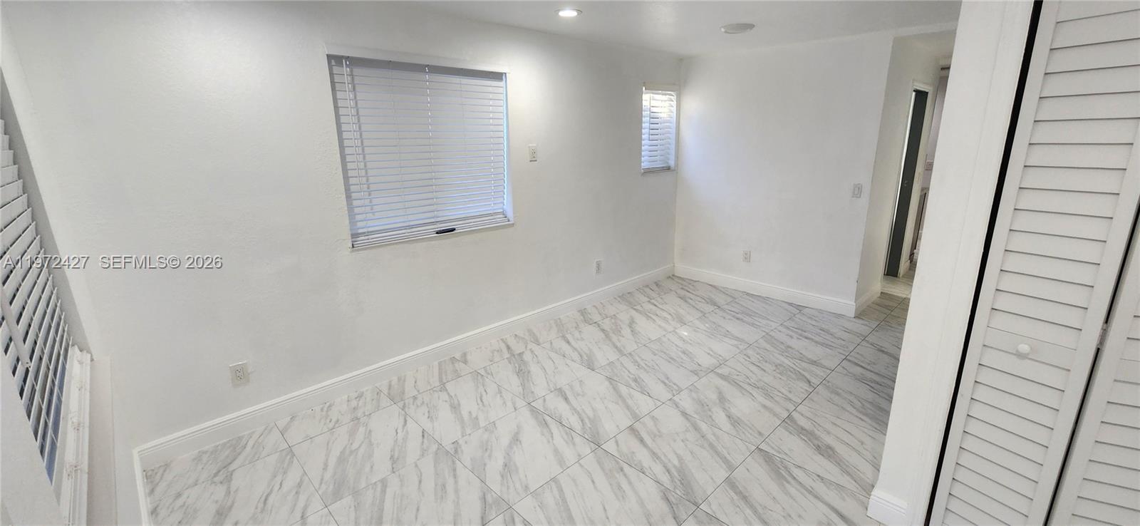 A bright room features white walls, marble-patterned tile flooring, and two windows with blinds — 1490/1492 NW 38th St, Miami FL 33142, MIAMI, FL