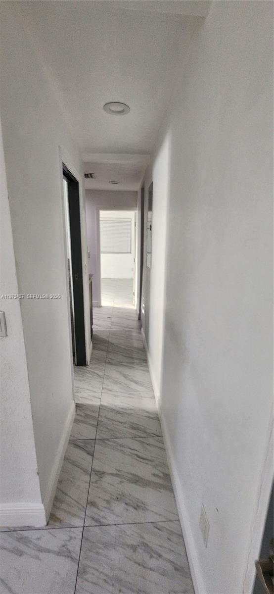 A narrow hallway features white walls, recessed lighting, and light-colored marble-patterned tile flooring — 1490/1492 NW 38th St, Miami FL 33142, MIAMI, FL
