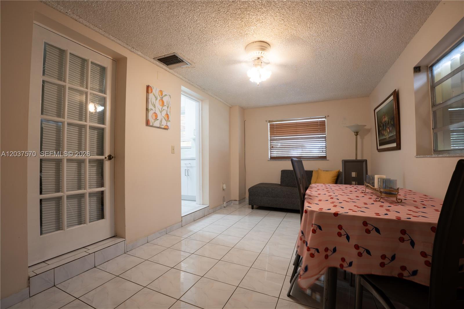 A dining area features a tiled floor, a cherry-patterned tablecloth, and a glass-paned door — 7899 NW 174th Ter, Hialeah FL 33015, HIALEAH, FL