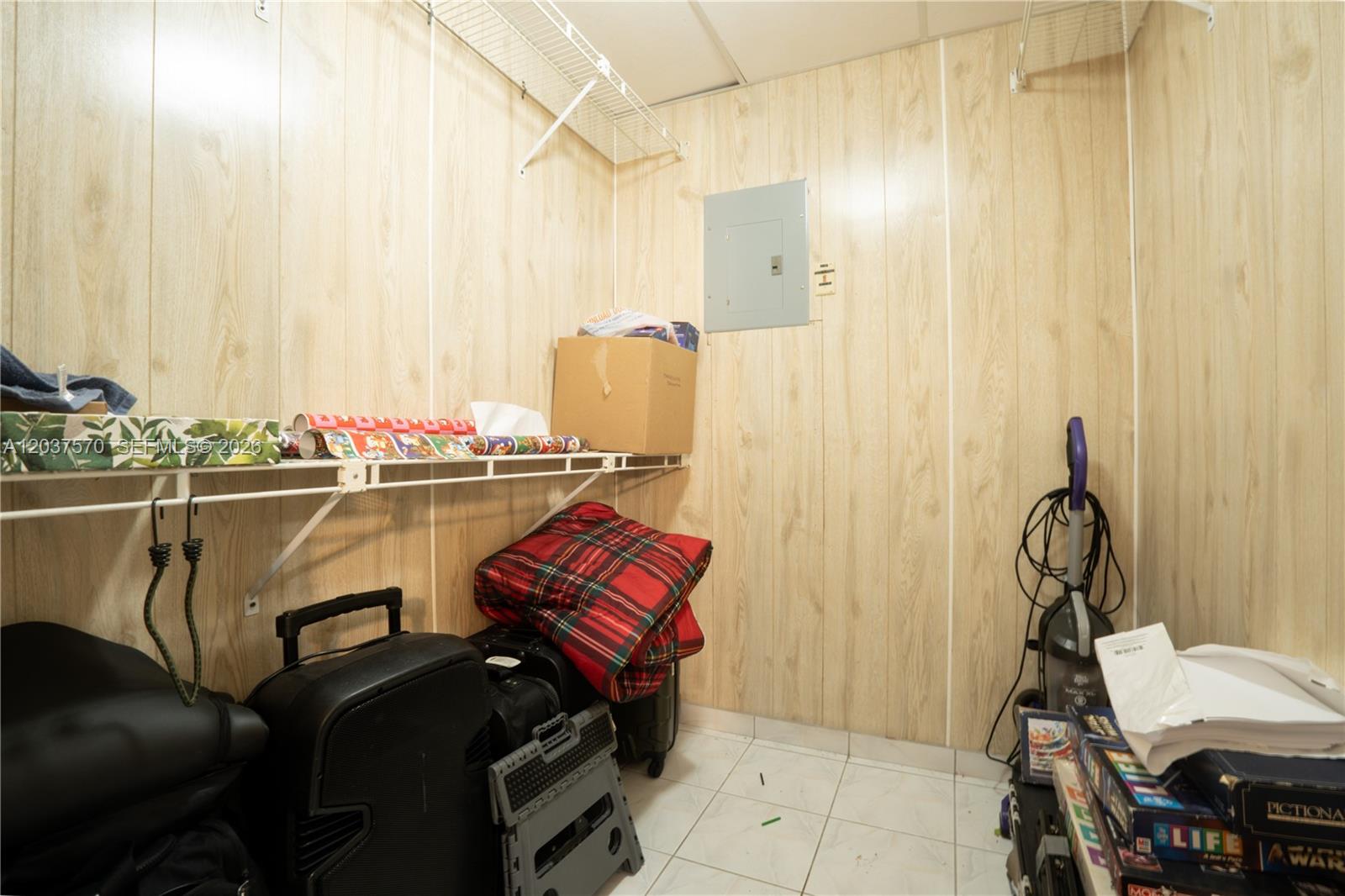 A storage closet with wood-paneled walls, white wire shelving, and a gray electrical panel — 7899 NW 174th Ter, Hialeah FL 33015, HIALEAH, FL
