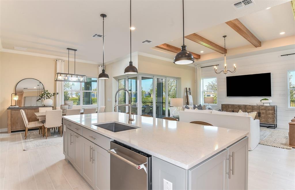 A kitchen island with a sink and dishwasher overlooks an open-concept dining and living area — 6208 SW 82ND TERRACE ROAD, OCALA, FL