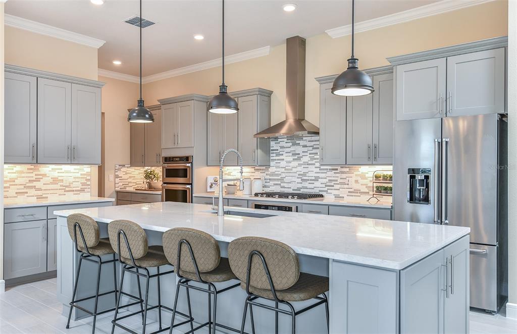 A modern kitchen features gray cabinets, a large white island with stools, and stainless appliances — 6208 SW 82ND TERRACE ROAD, OCALA, FL
