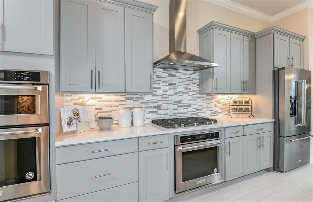A modern kitchen features gray cabinets, stainless steel appliances, and a tiled backsplash — 6208 SW 82ND TERRACE ROAD, OCALA, FL