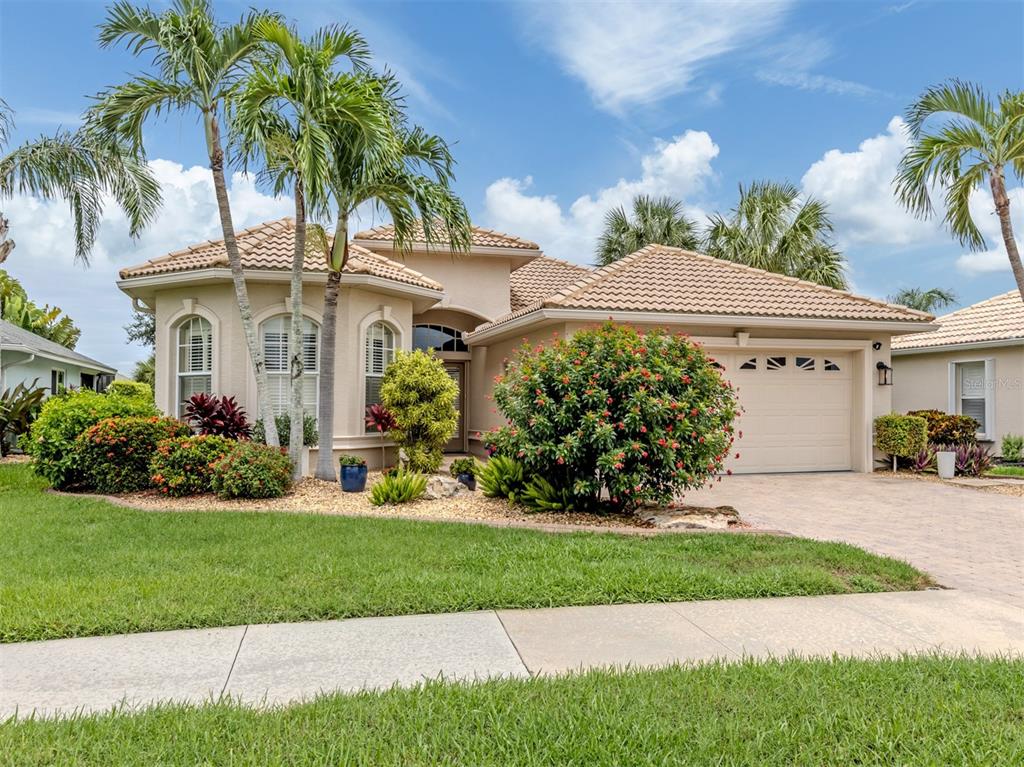 A single-story beige stucco house with a tiled roof, palm trees, and a two-car garage — 151 COCO PALM DRIVE, VENICE, FL