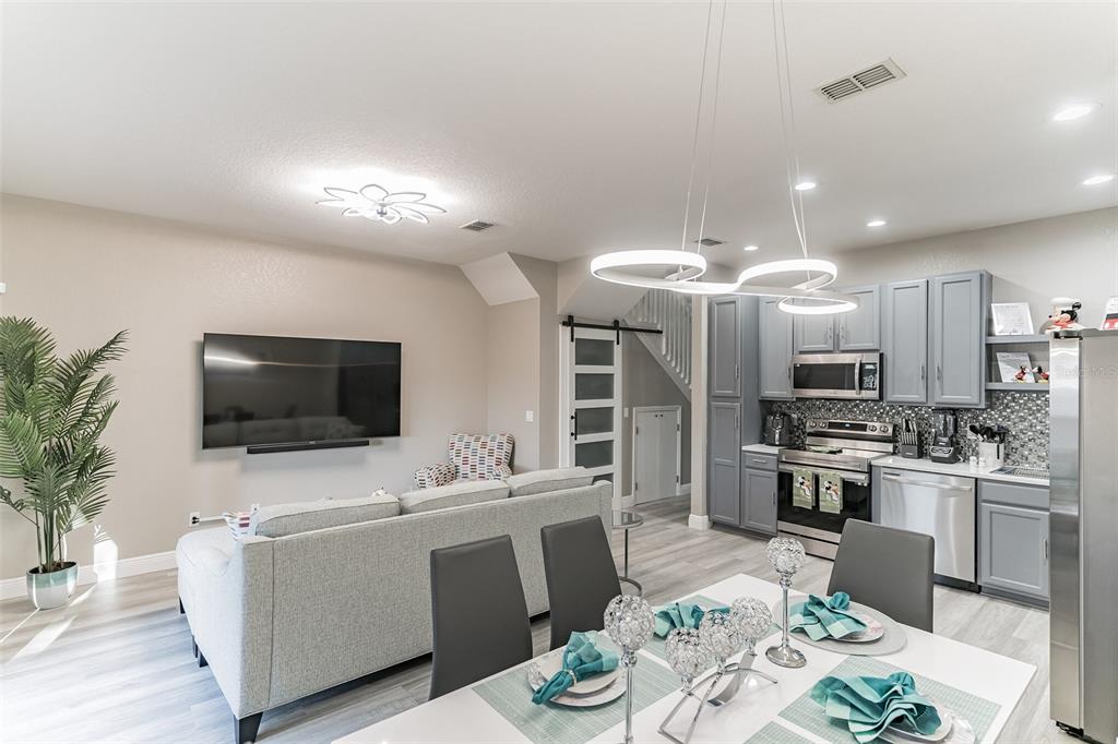 An open-concept living area features a kitchen with grey cabinets, a dining table, and sofa — 2468 CARAVELLE CIRCLE, KISSIMMEE, FL