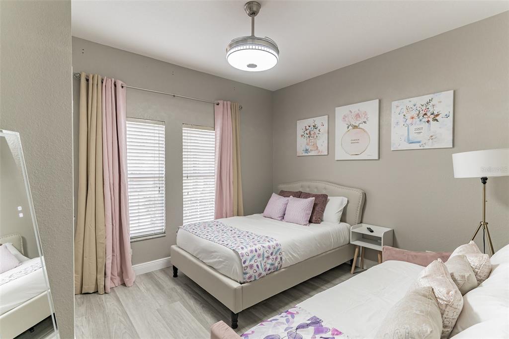 A bedroom features a bed, a floor lamp, light wood flooring, and wall art — 2468 CARAVELLE CIRCLE, KISSIMMEE, FL