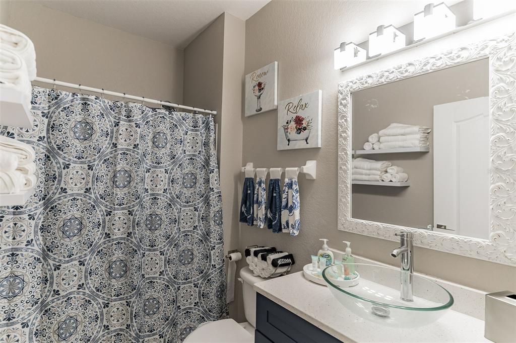 A bathroom features a patterned shower curtain, a glass vessel sink, and white wall shelves — 2468 CARAVELLE CIRCLE, KISSIMMEE, FL