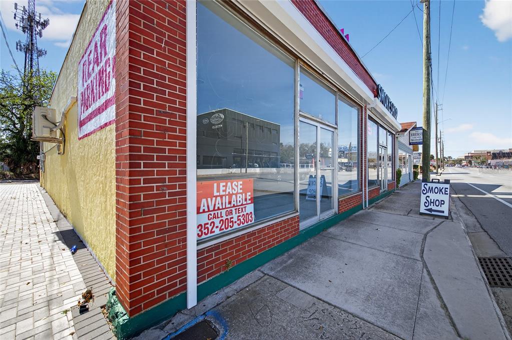 A brick and yellow commercial building exterior features large glass windows and a lease sign — 517 W INTERNATIONAL SPEEDWAY BOULEVARD, DAYTONA BEACH, FL