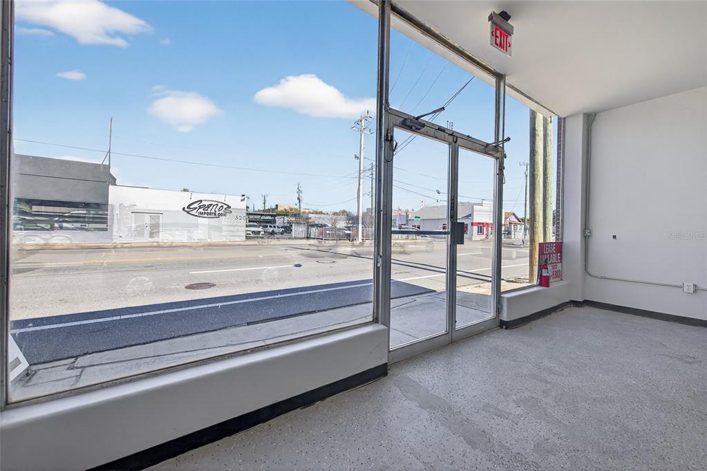 An empty commercial space features large glass storefront windows, a double door, and concrete flooring — 517 W INTERNATIONAL SPEEDWAY BOULEVARD, DAYTONA BEACH, FL