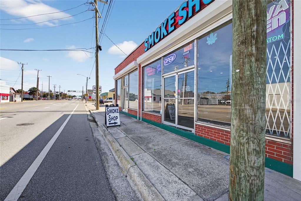 A brick-front smoke shop building sits along a street with a sidewalk and utility pole — 517 W INTERNATIONAL SPEEDWAY BOULEVARD, DAYTONA BEACH, FL
