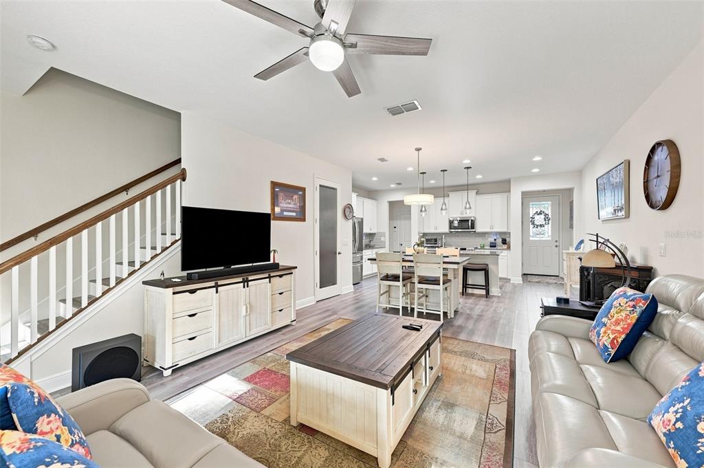 An open-concept living room and kitchen featuring light wood flooring and a staircase — 17815 ALTHEA BLUE PLACE, LUTZ, FL
