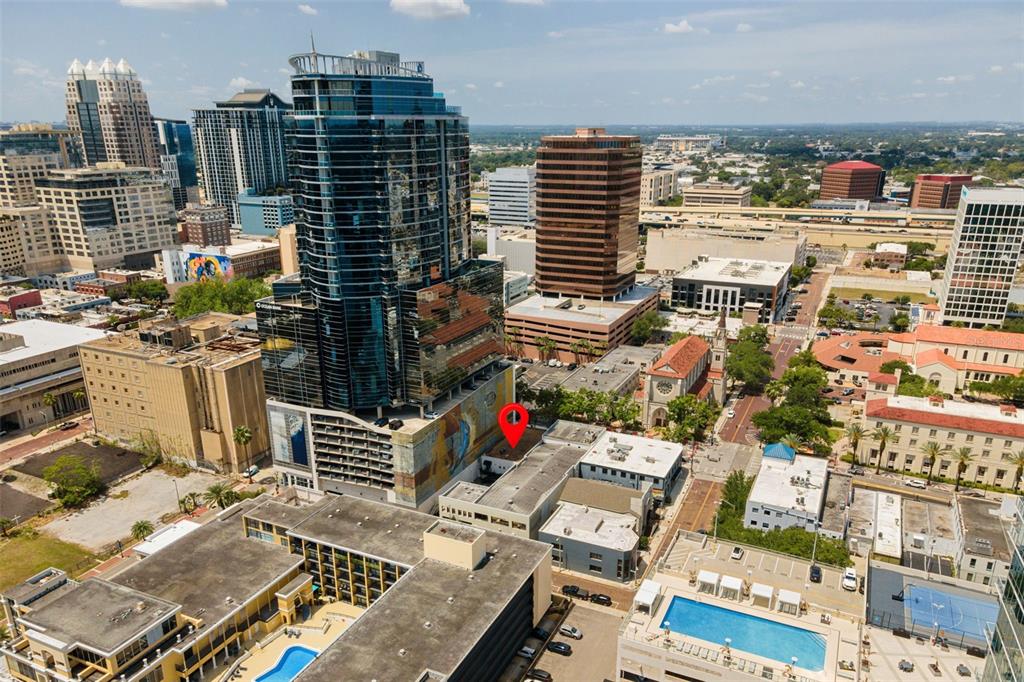An aerial view of a city skyline featuring a tall glass skyscraper and a red pin — 127 N MAGNOLIA AVENUE, ORLANDO, FL