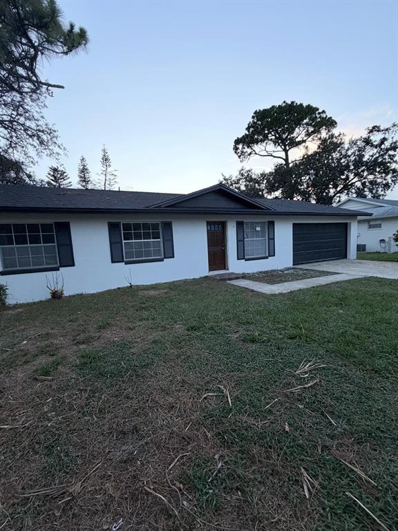 A single-story house with white stucco walls, a dark roof, and a dark garage door — 115 MEADOWFIELD LANE, LONGWOOD, FL