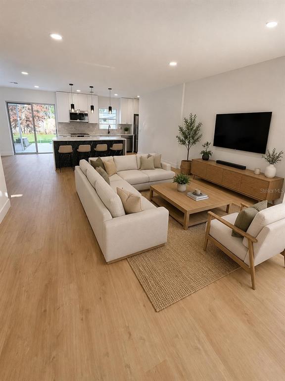 An open-concept living room and kitchen feature light wood flooring, neutral furniture, and recessed lighting — 115 MEADOWFIELD LANE, LONGWOOD, FL