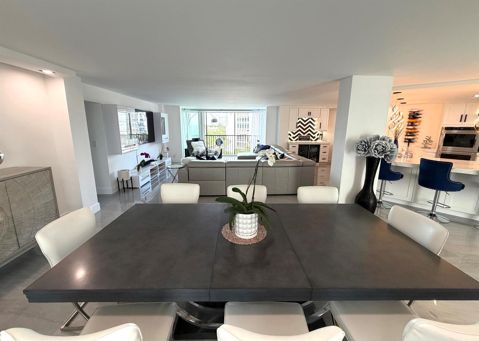 A modern living room features a large grey sectional, blue pillows, and a glass coffee table — 1627 Riverview Road # 615, Deerfield Beach FL 33441, DEERFIELD BEACH, FL
