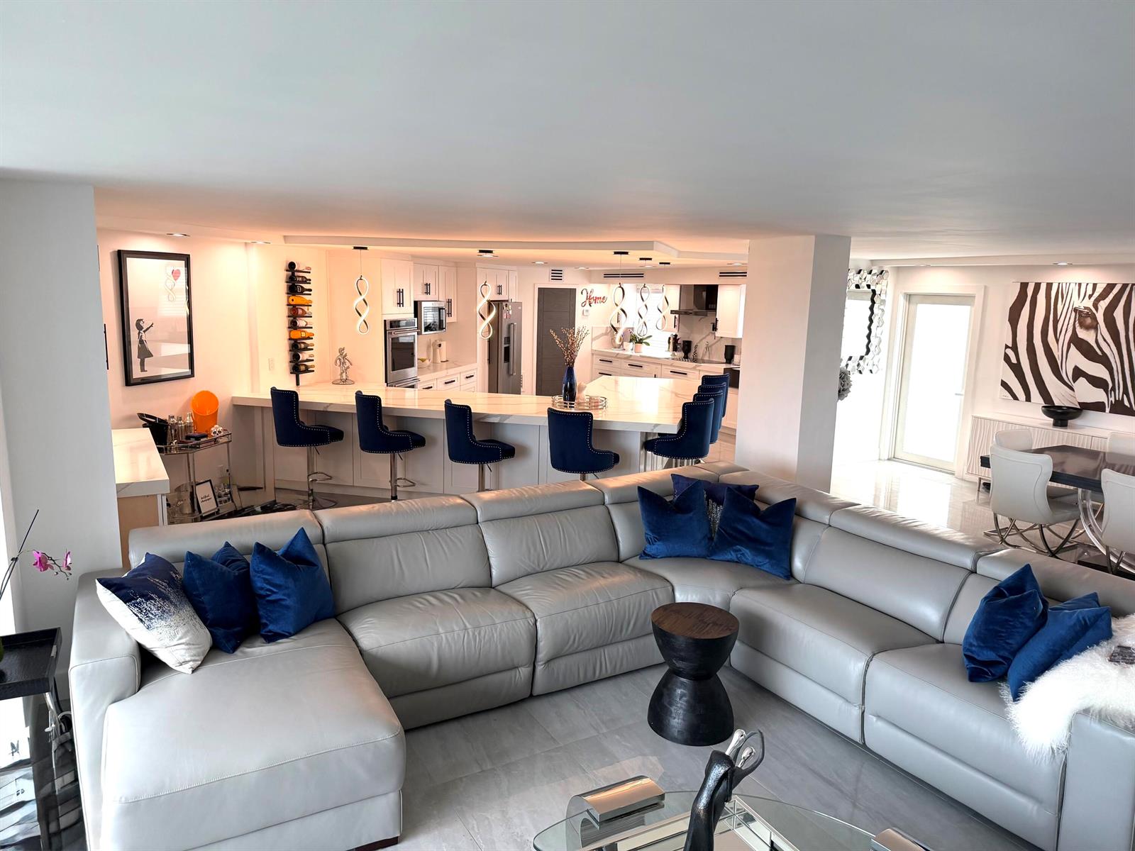A modern white kitchen features marble countertops, black hardware, and a large central island — 1627 Riverview Road # 615, Deerfield Beach FL 33441, DEERFIELD BEACH, FL