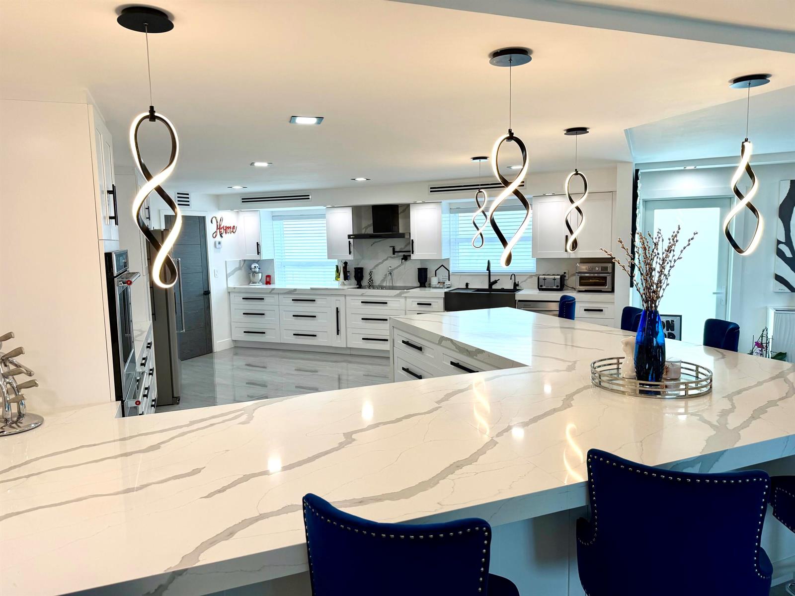 A modern kitchen features white cabinets, marble countertops, a black farmhouse sink, and stainless appliances — 1627 Riverview Road # 615, Deerfield Beach FL 33441, DEERFIELD BEACH, FL