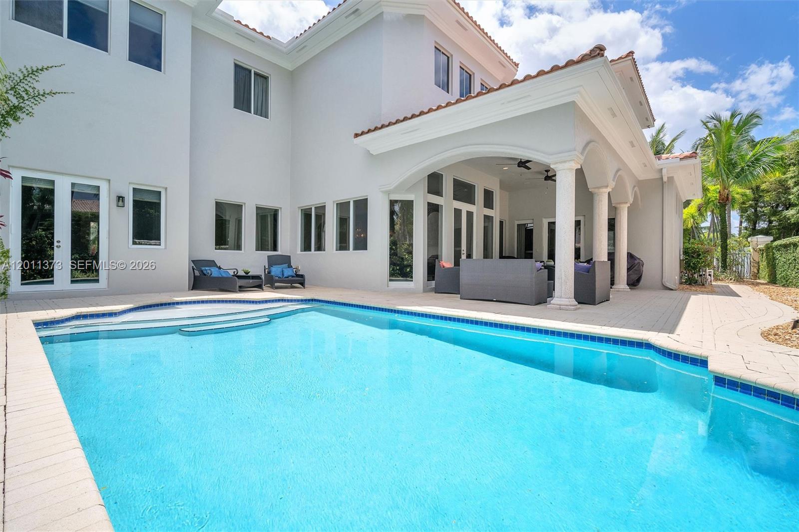 A swimming pool sits in front of a two-story house with a covered patio — 1480 Windjammer Way, Hollywood FL 33019, HOLLYWOOD, FL