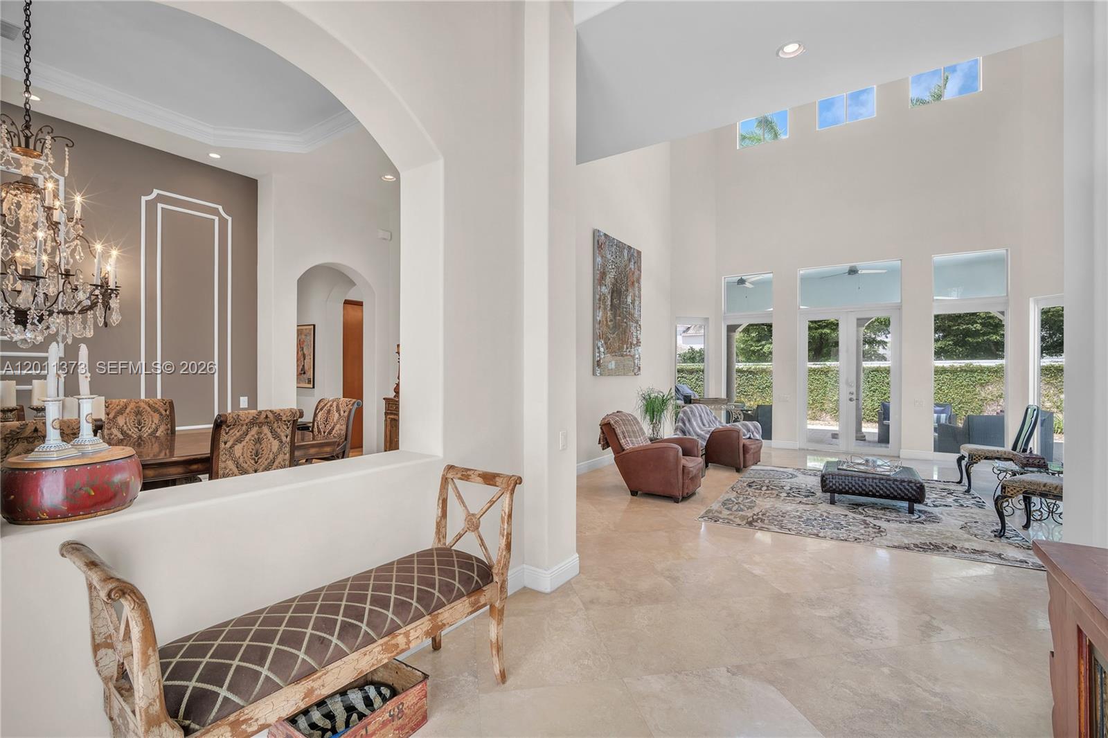 An open living and dining area features high ceilings, tile floors, and large glass doors — 1480 Windjammer Way, Hollywood FL 33019, HOLLYWOOD, FL