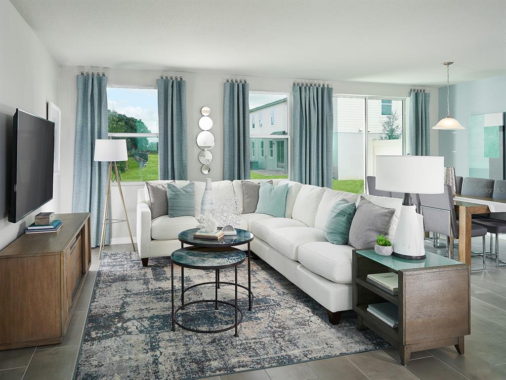 A living room features a white sectional sofa, blue curtains, and a patterned area rug — 4531 RANGELAND WAY, ST CLOUD, FL