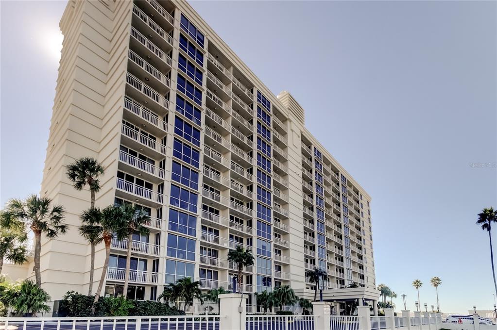 A tall, multi-story residential building with balconies and palm trees under a clear sky — 100 PIERCE STREET UNIT 305, CLEARWATER, FL