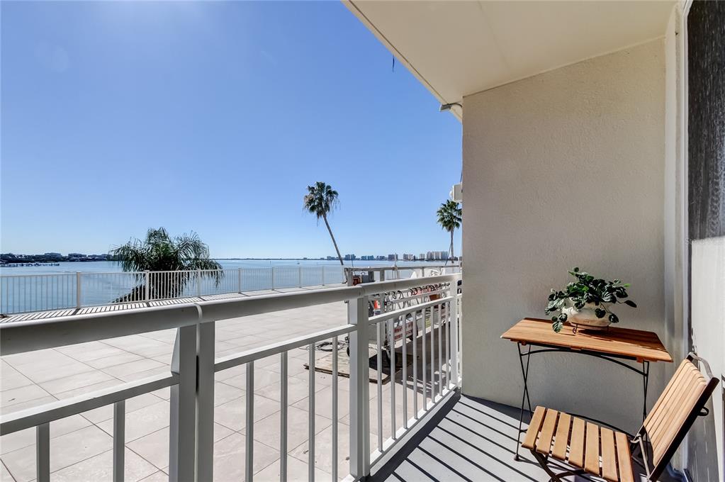 A balcony with a white railing overlooks a large body of water and palm trees — 100 PIERCE STREET UNIT 305, CLEARWATER, FL
