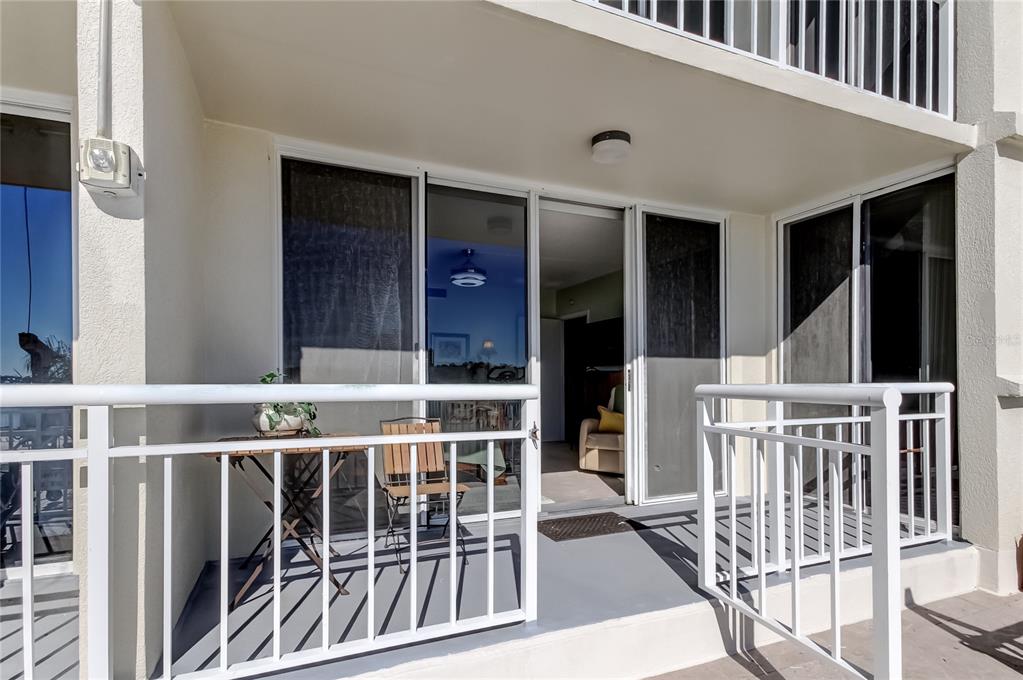 A balcony with a white railing, sliding glass doors, and a small table and chair — 100 PIERCE STREET UNIT 305, CLEARWATER, FL