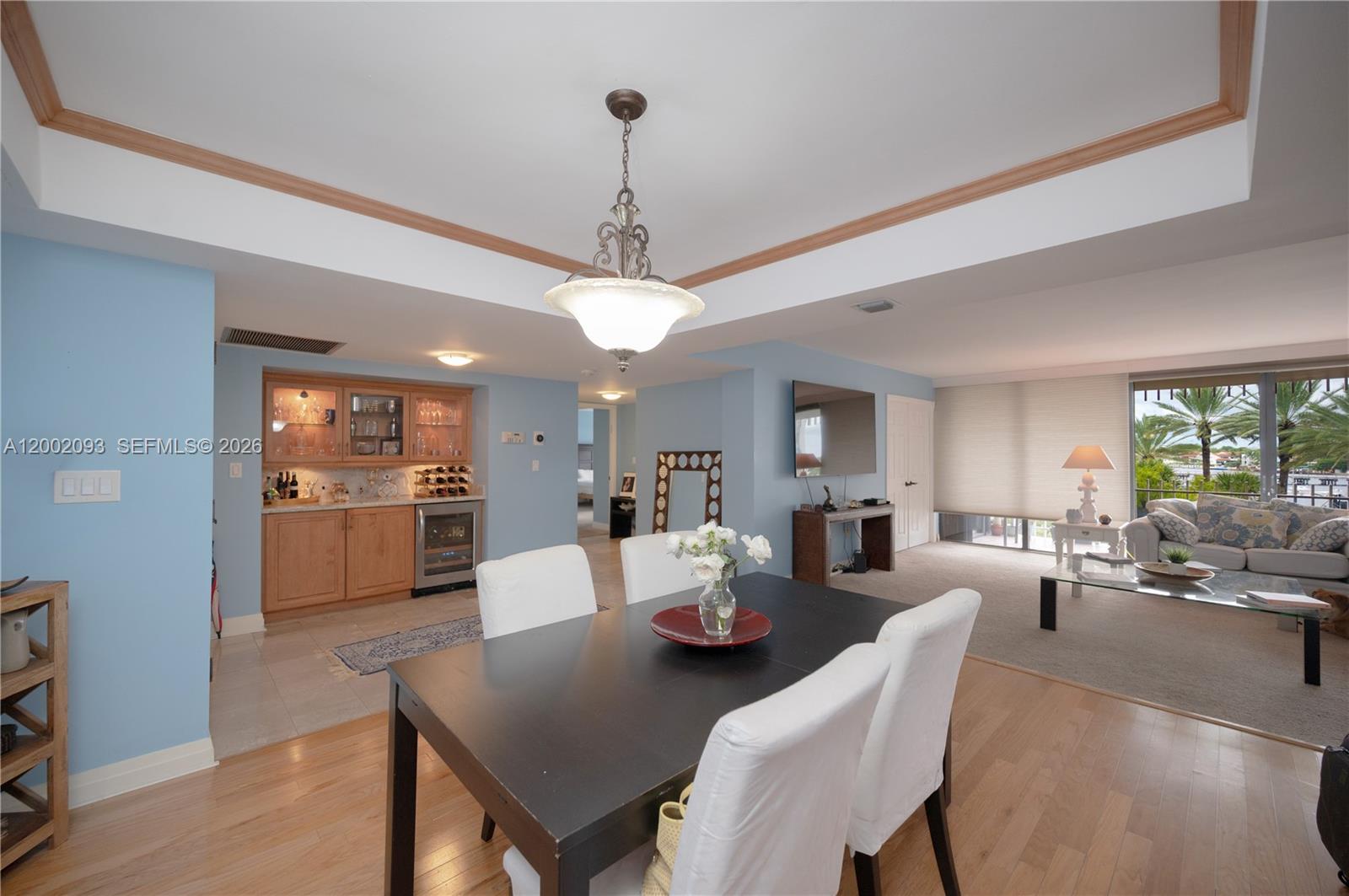 A dining area with a dark table and white chairs opens into a living room — 3 Grove Isle Dr # C308, Miami FL 33133, MIAMI, FL