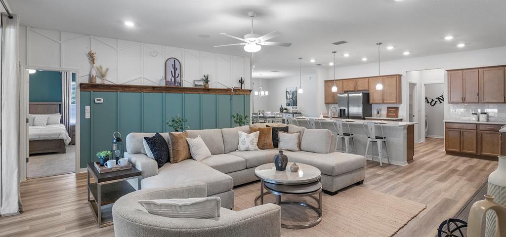 An open-concept living room features a teal accent wall, sectional sofa, and kitchen island — 10538 SW 76TH COURT, OCALA, FL