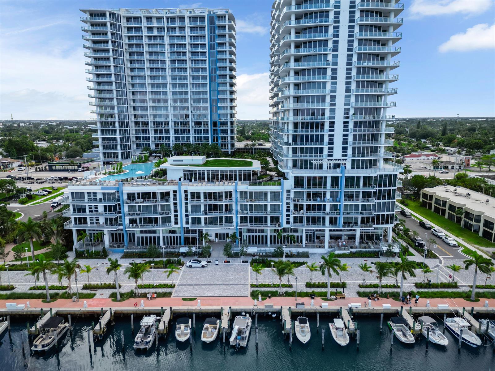 An aerial view shows two modern high-rise apartment buildings overlooking a marina with docked boats — 220 Lake Shore Drive # 1908, Lake Park FL 33403, LAKE PARK, FL