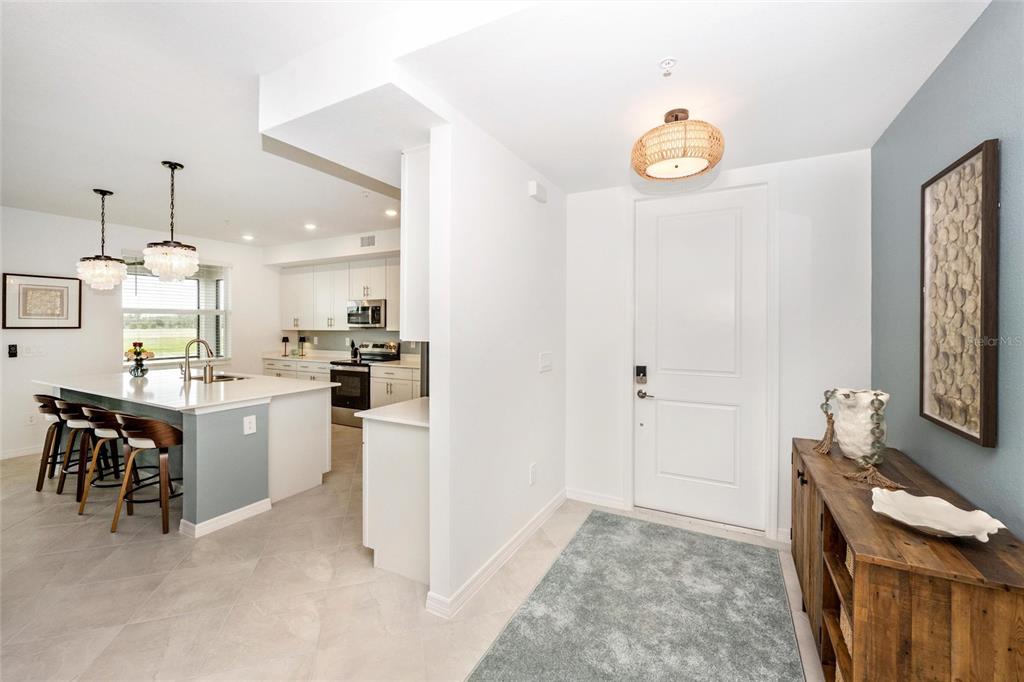 An entryway leads into a kitchen with a white island, bar seating, and light tile — 12967 BLACKBERRY COURT UNIT 102, VENICE, FL