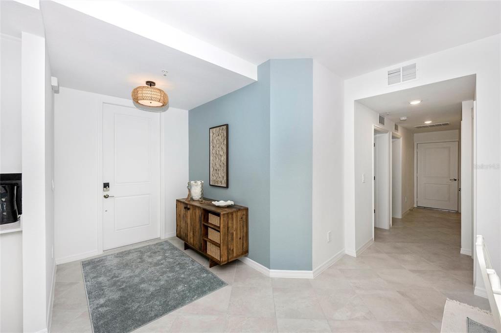 An entryway features a light blue accent wall, a wooden console table, and tile flooring — 12967 BLACKBERRY COURT UNIT 102, VENICE, FL