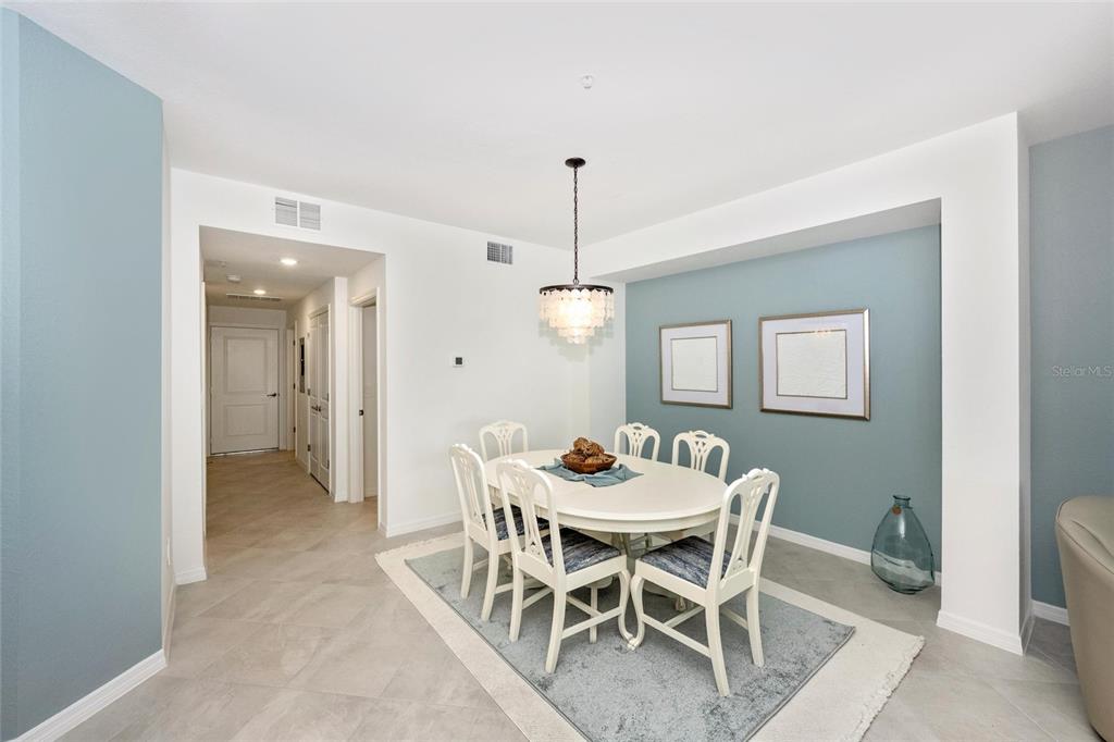 A dining room features a white table, six chairs, a chandelier, and blue accent walls — 12967 BLACKBERRY COURT UNIT 102, VENICE, FL