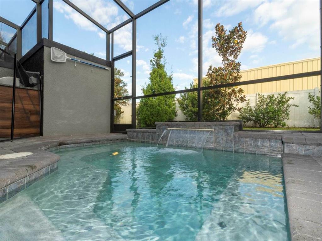 A screened-in patio features a small swimming pool with a stone waterfall feature — 4425 LE REVE COURT, KISSIMMEE, FL