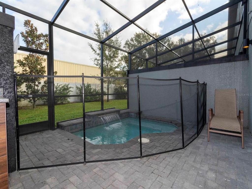 A screened-in patio features a small pool with a waterfall and a mesh safety fence — 4425 LE REVE COURT, KISSIMMEE, FL