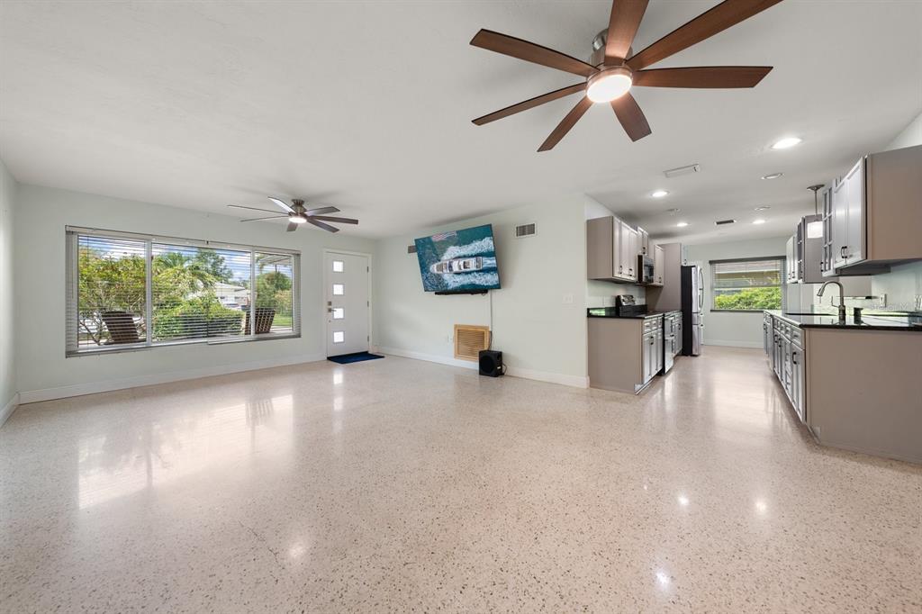 An open-concept living room and kitchen featuring light-colored terrazzo flooring and two ceiling fans — 101 S NEPTUNE AVENUE, CLEARWATER, FL