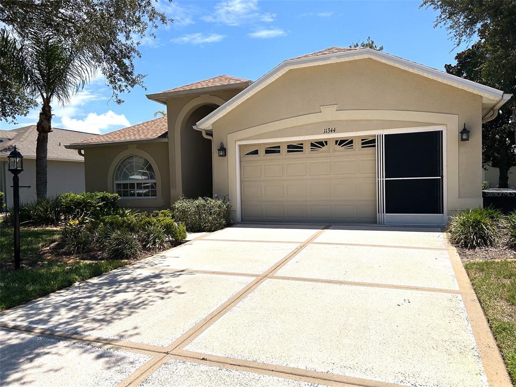 A tan single-story house with a two-car garage and a concrete driveway — 11344 HERITAGE POINT DRIVE, HUDSON, FL