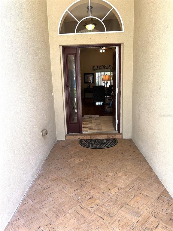 A front entryway features a tiled porch, a glass-paneled door, and an arched transom window — 11344 HERITAGE POINT DRIVE, HUDSON, FL