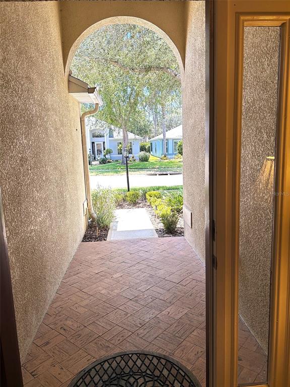 A view from an arched entryway looking out onto a paved walkway and suburban street — 11344 HERITAGE POINT DRIVE, HUDSON, FL